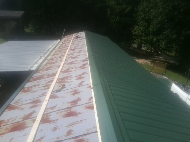 Old rusted panels beside newly installed green metal roofing — Wind Damage Roof Repair by Roofing Brothers in Wausau