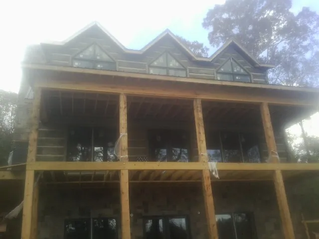 Dormers and porch framing on a large log home under construction — Roof Coating work by our crew in Wausau
