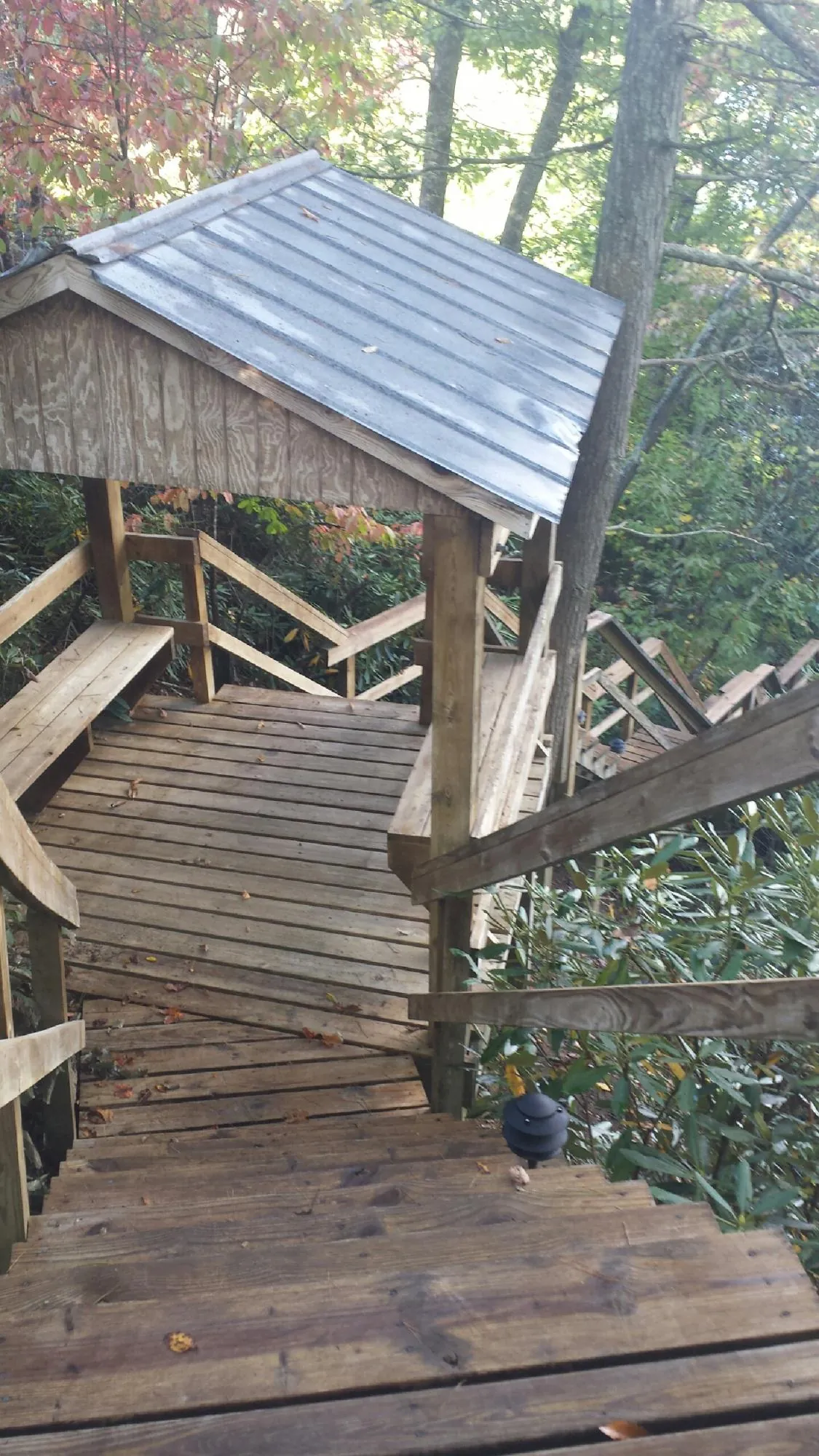 Metal roofed shelter over wooden steps on a wooded walkway — Skylight Repair & Installation work by our crew in Wausau