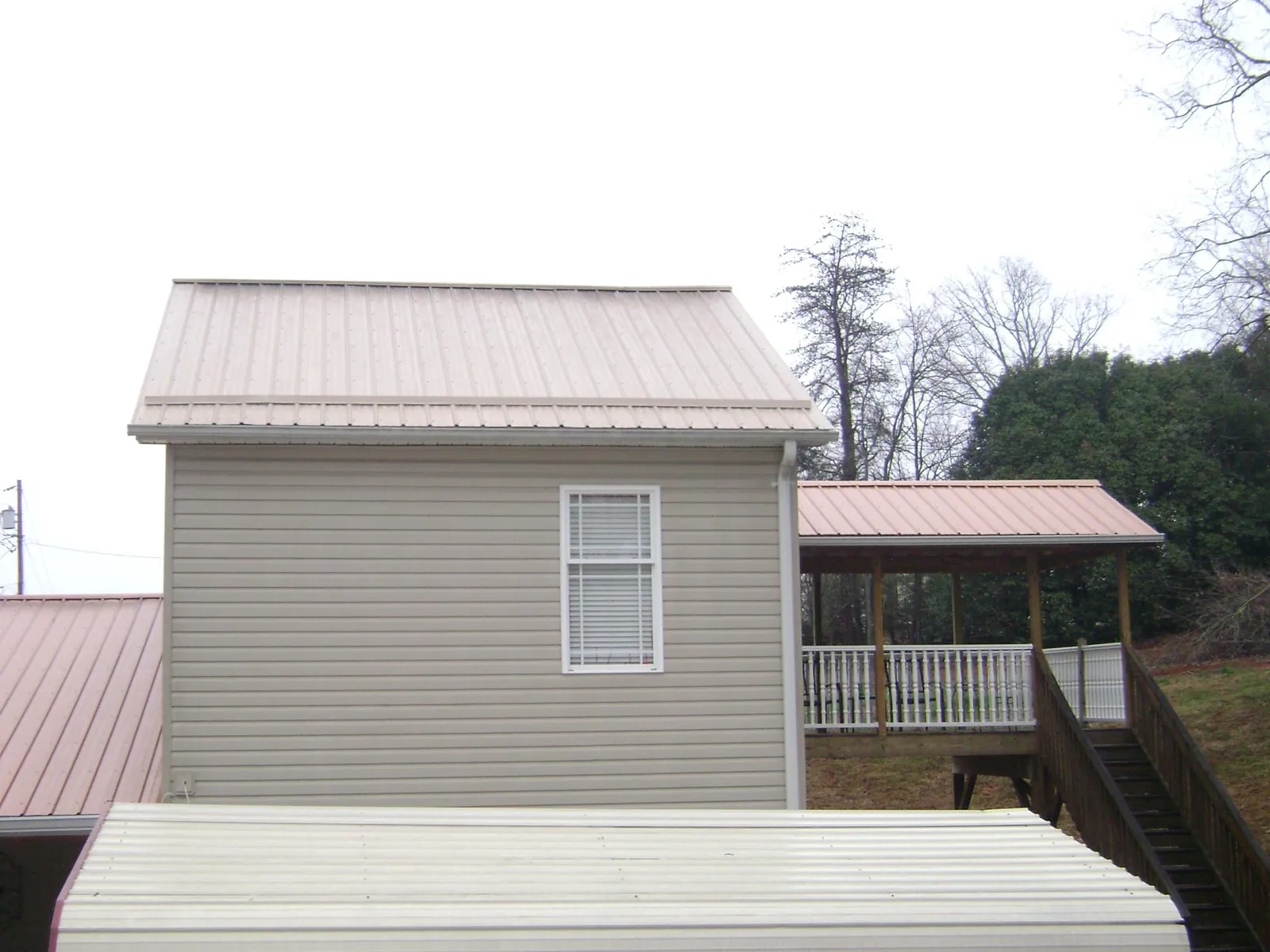 Tan metal roofs on a two story addition and attached porch, from a Roof Replacement job in Wausau