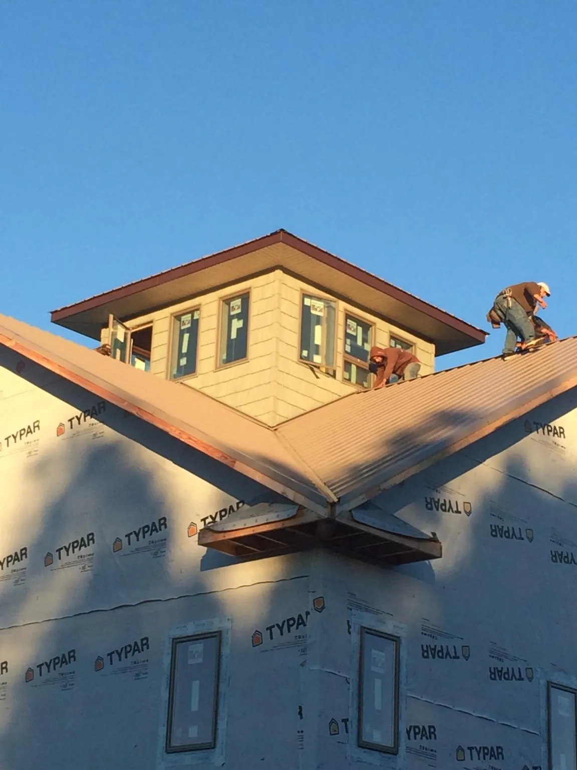 Roofers working around a rooftop cupola on a new metal roof at sunset — Roof Waterproofing in Wausau by Roofing Brothers